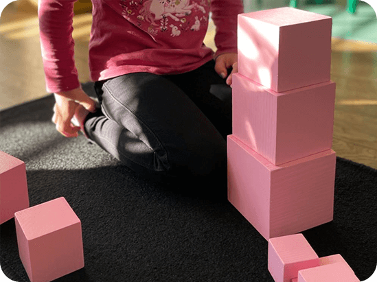 Enfant à genou jouant avec des cubes roses